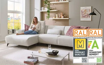 Frau sitzt auf gemütlichen weißem Sofa und entspannt.